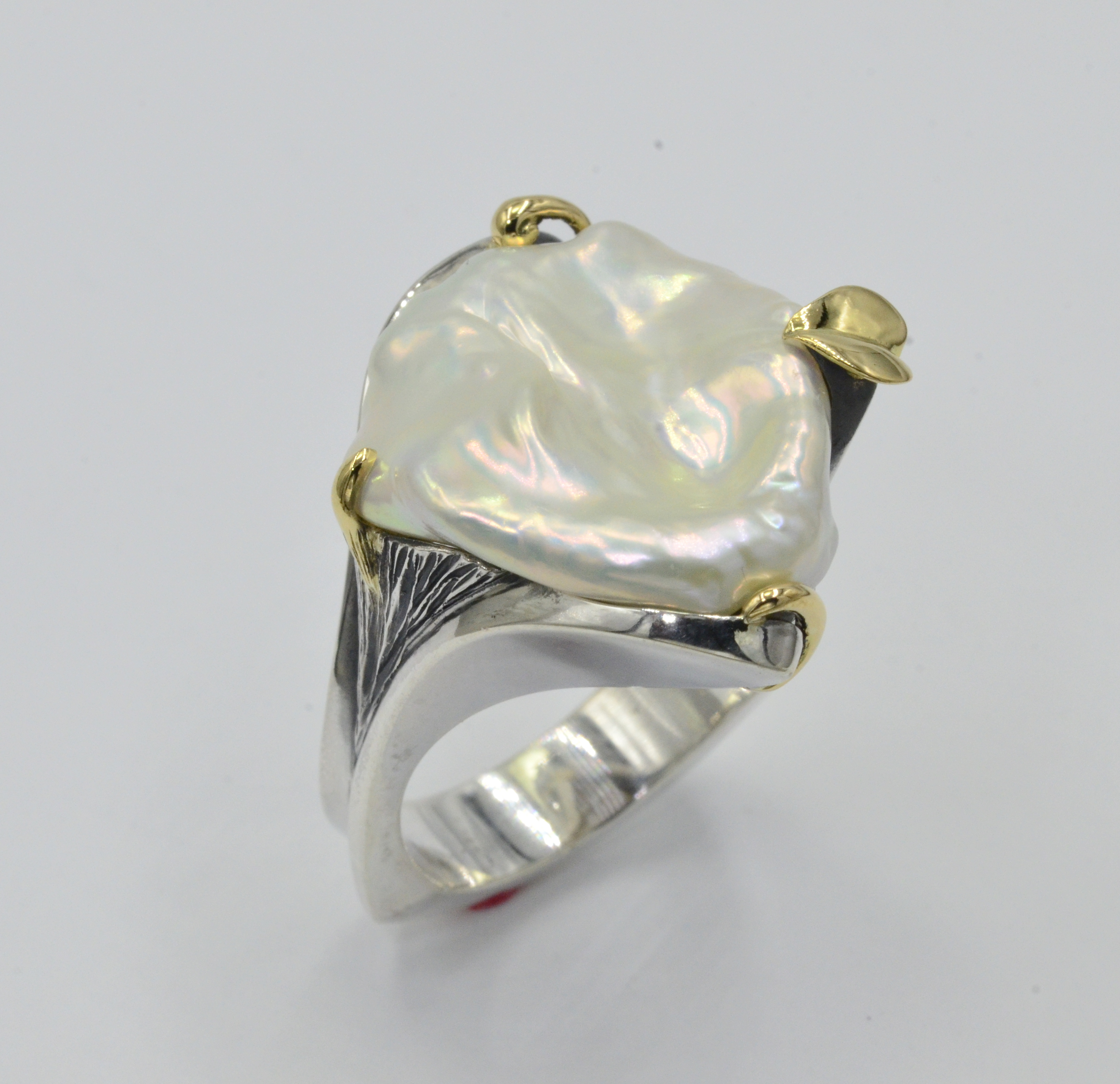 This ring presents itself as having a strong stance while being fluid and gentle. From the top view all you see is a beautiful White Freshwater Pearl held in place by gold leafs. The sides are graceful twist and turns. Classic Yanke Designs ! Pearl approximately 1" diameter.